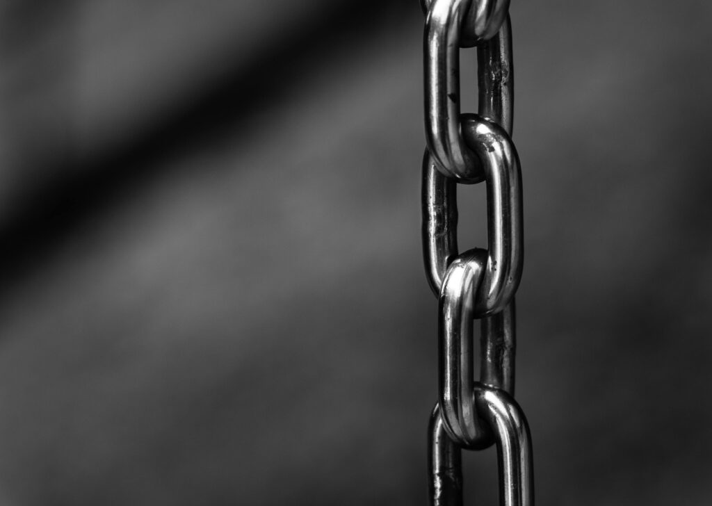 Detailed close-up of a strong shiny metallic chain link against a blurred background, emphasizing security.