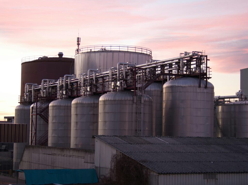 A refinery with large stainless steel storage tanks during sunset, showcasing industrial infrastructure.